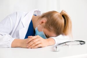 Tired and exhausted nurse or doctor. Stressed female medical worker with protective face mask